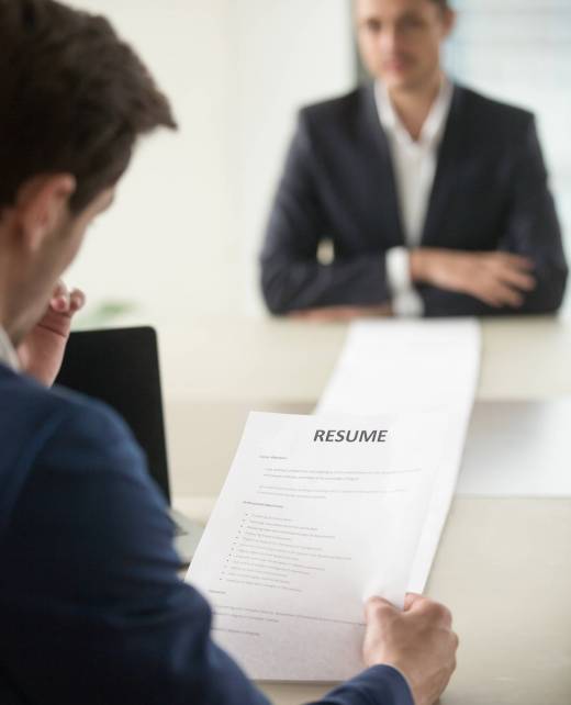 Interviewer reading applicants long resume Back view of employer reading resume focus on document, job applicant waiting for hiring decision at desk on background. Hiring manager studying long list of candidates achievements and experiences
